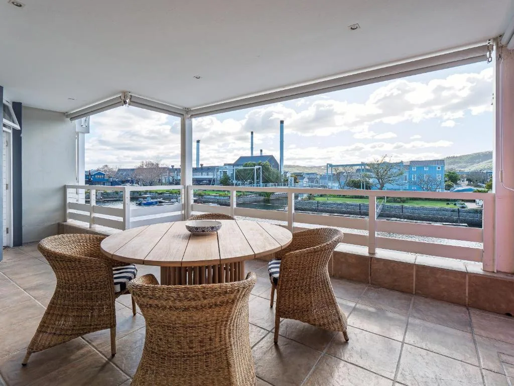 Covered deck with round dining table and woven chairs overlooking lagoon
