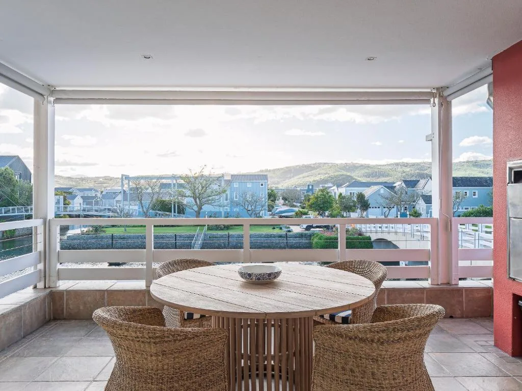 Covered patio with round dining table overlooking Knysna lagoon and mountains