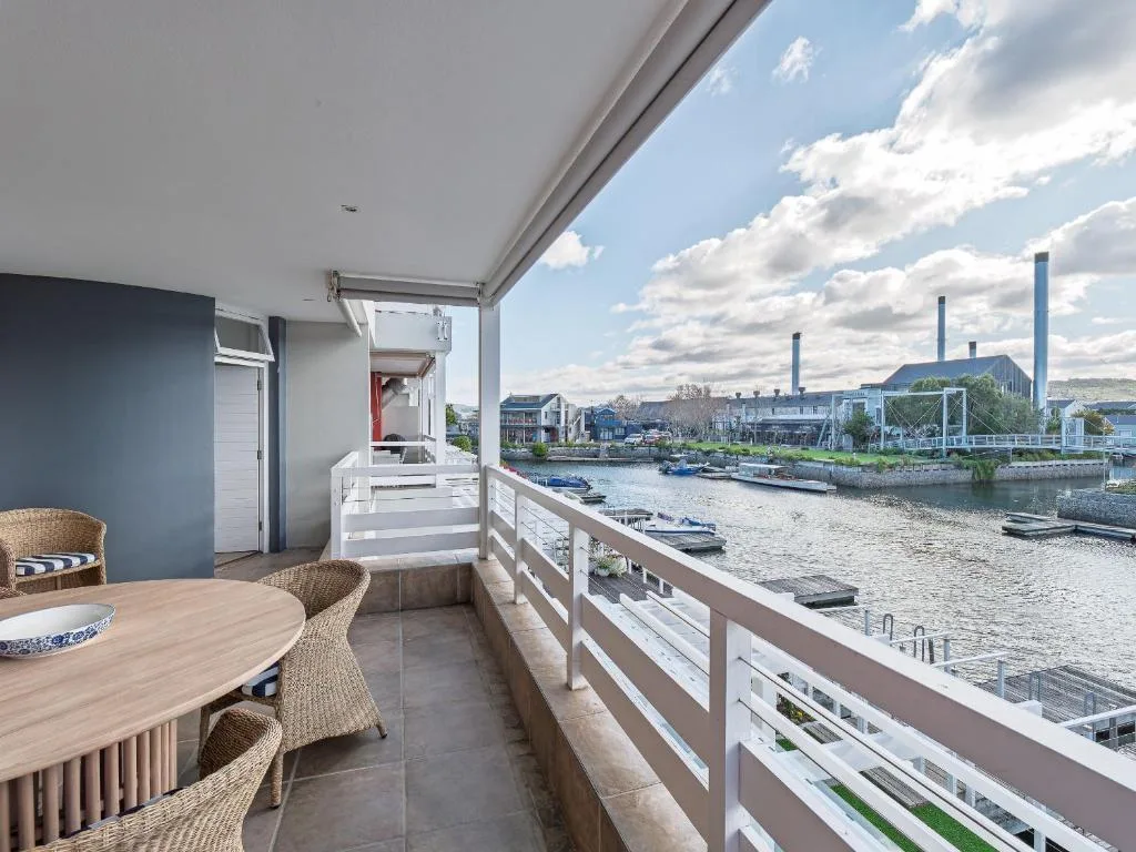 Covered waterfront balcony with dining table overlooking Knysna lagoon and boats