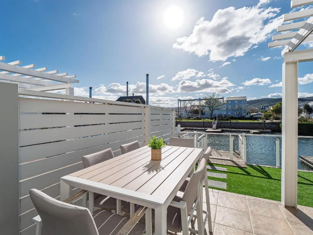 Waterfront patio with dining table, pergola, and lagoon views