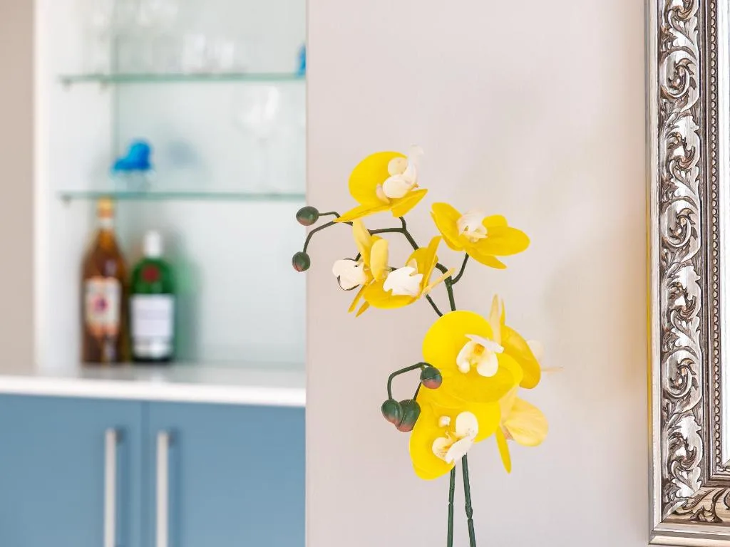 Yellow orchids in vase with ornate frame and kitchen background
