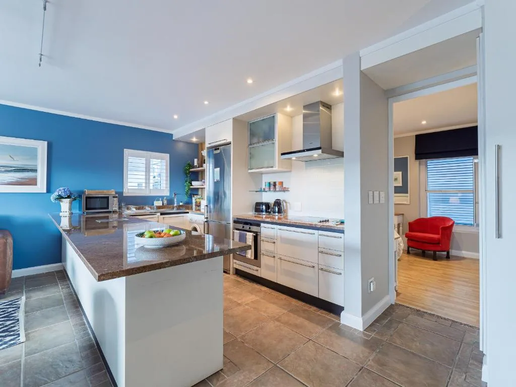Modern kitchen with stainless steel appliances, white cabinetry, dark countertop island