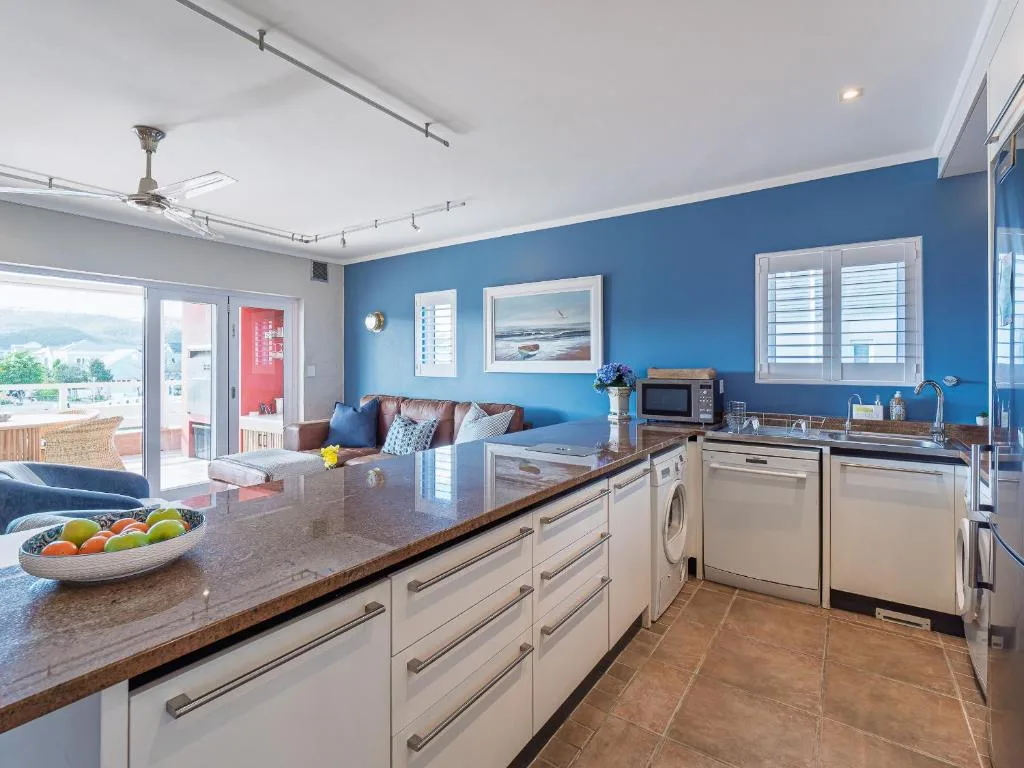 Modern kitchen with cream cabinetry, granite counters, and open-plan lounge beyond