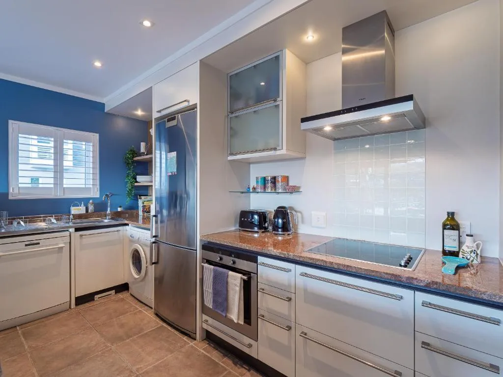 Modern kitchen with stainless steel appliances, granite counters, and blue accent wall