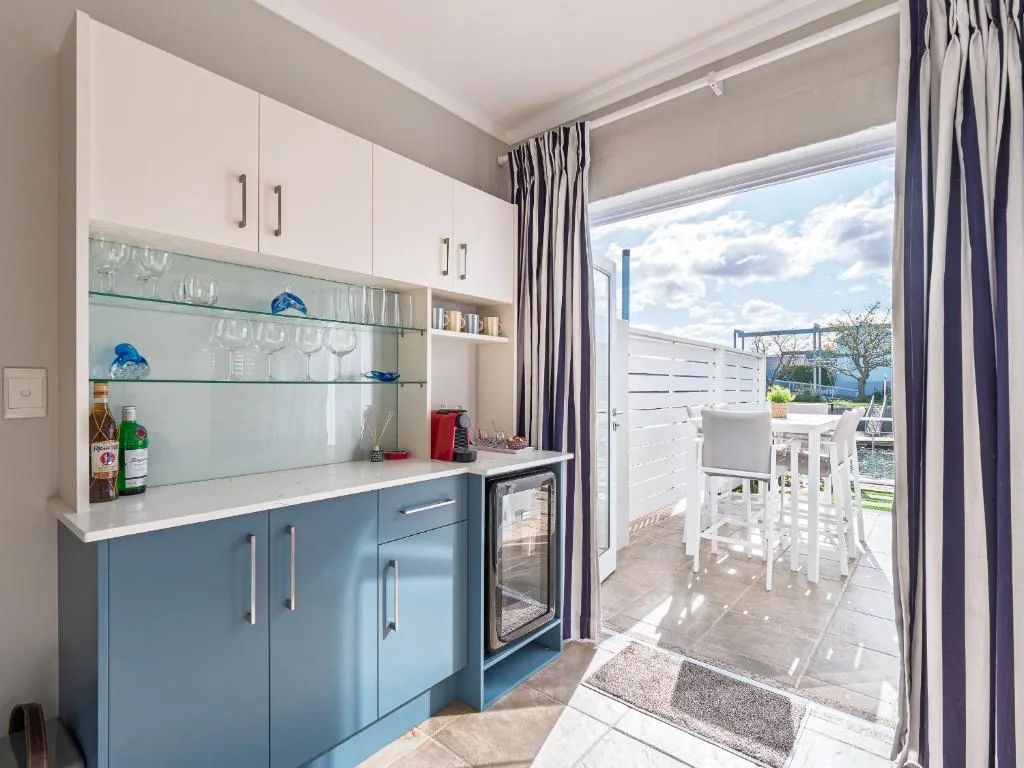 Modern kitchen with blue cabinetry, white countertop, and glass backsplash shelving