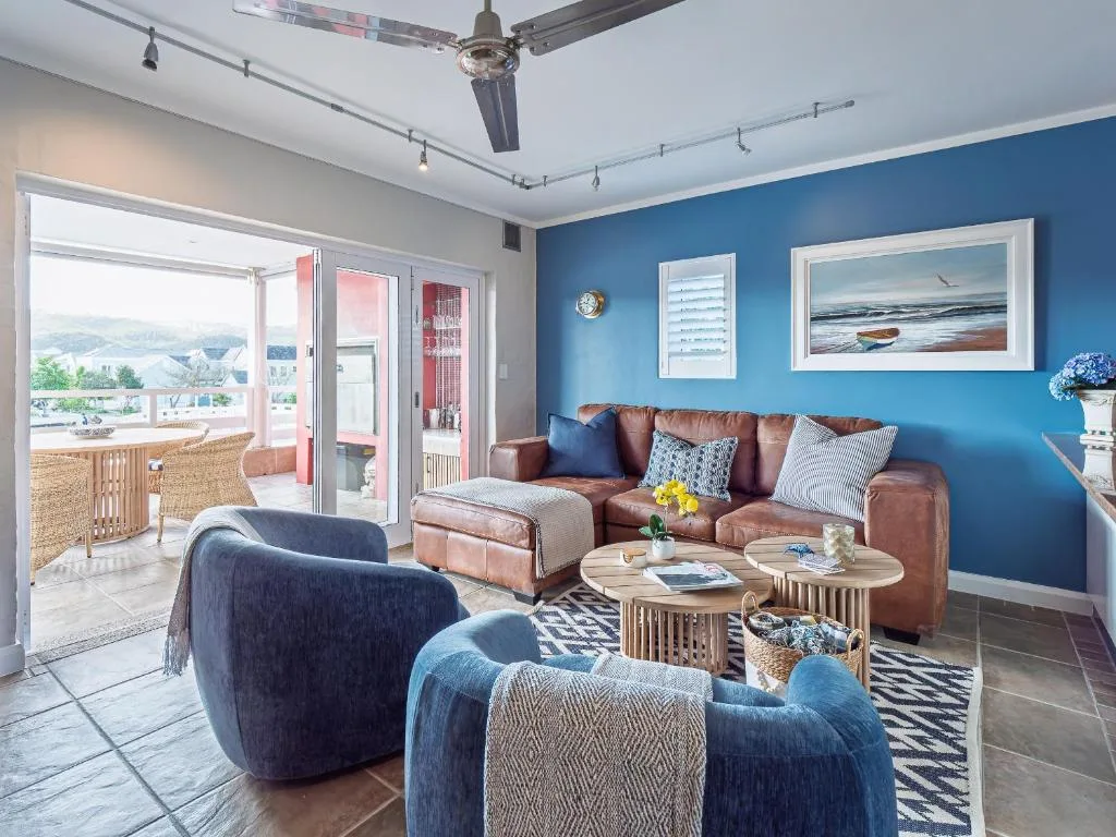 Bright lounge with blue walls, leather sofa, and lagoon views through glass doors