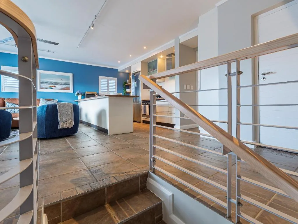 Modern open-plan lounge with blue accent wall and wooden staircase railing
