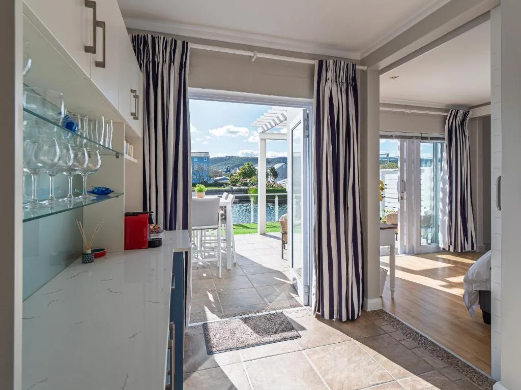 Modern lounge with open-plan kitchen, striped curtains, and lagoon view doors