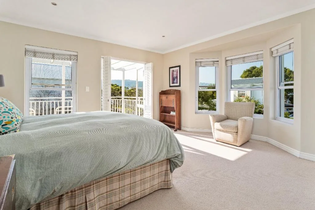 Spacious master bedroom with bed, armchair, and scenic water views through multiple windows