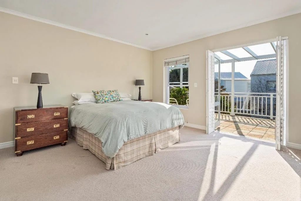 Bright bedroom with queen bed, wooden nightstand, and deck access