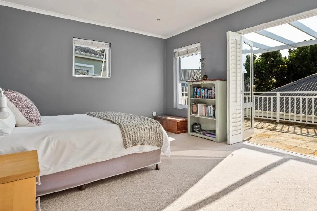 Bright bedroom with queen bed, gray walls, and French doors opening to deck