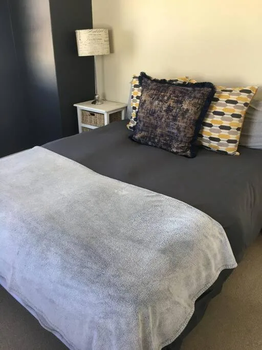 Bedroom with gray bed, decorative pillows, and bedside lamp