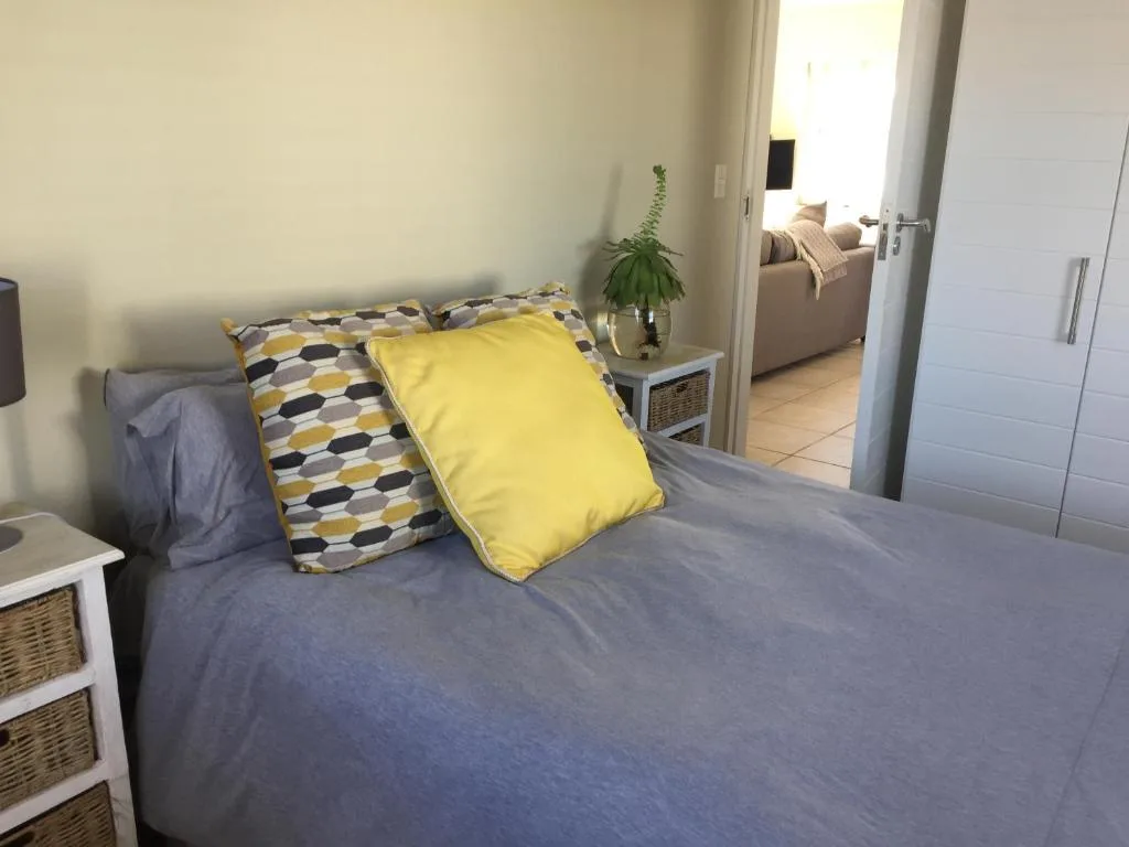 Bedroom with queen bed, yellow and patterned pillows, wicker storage