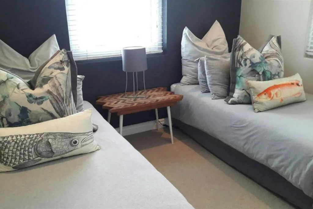 Twin beds with decorative fish-patterned pillows and natural light from windows