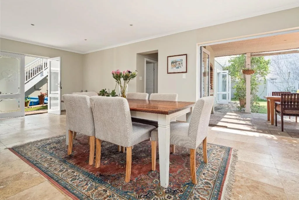 Spacious dining area with wooden table and upholstered chairs, opens to garden