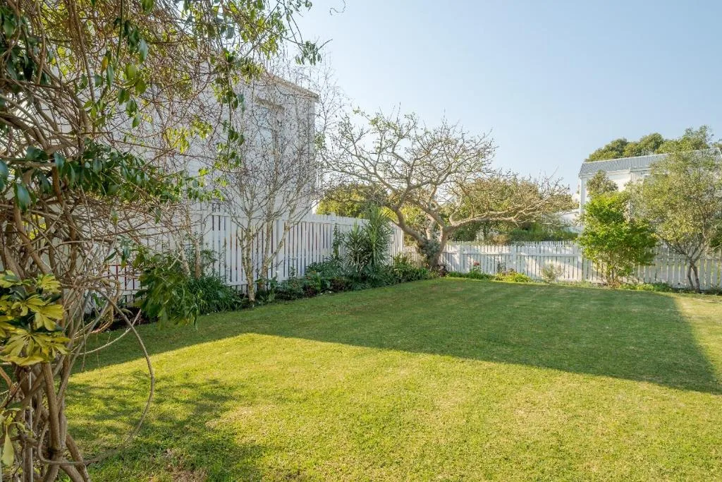 Spacious green garden with mature trees and white cottage buildings