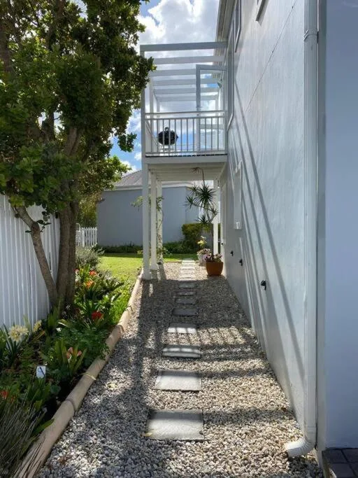 Modern white cottage exterior with gravel pathway and upper deck balcony