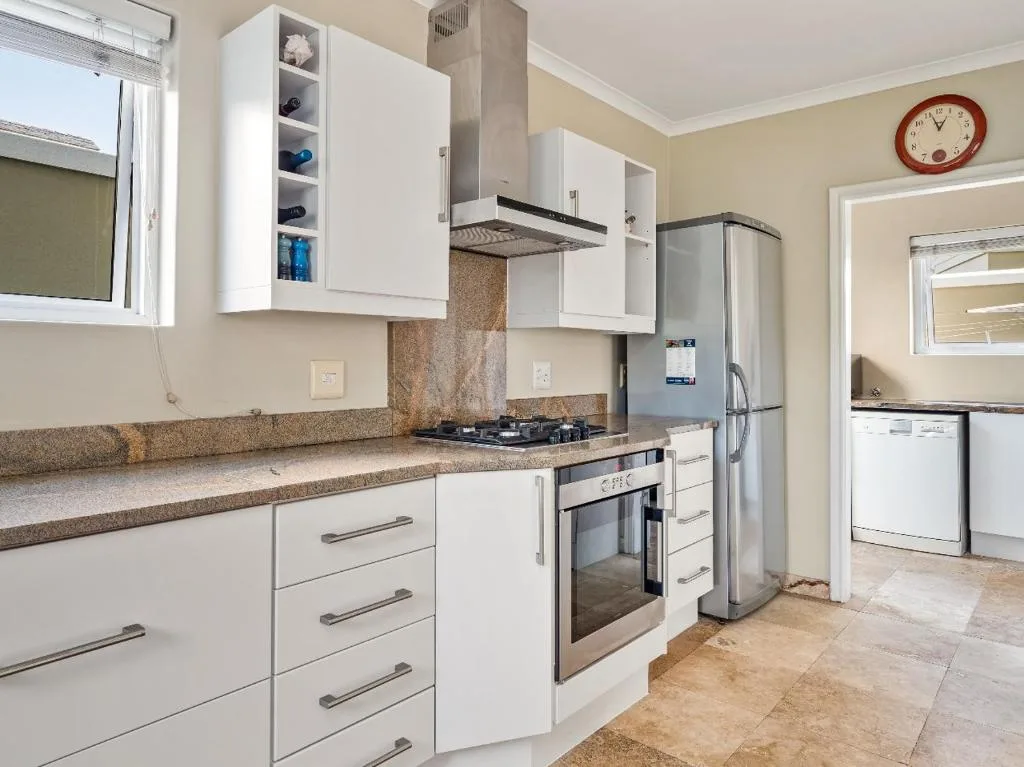 Modern kitchen with white cabinetry, granite countertops, gas stove, and stainless steel appliances