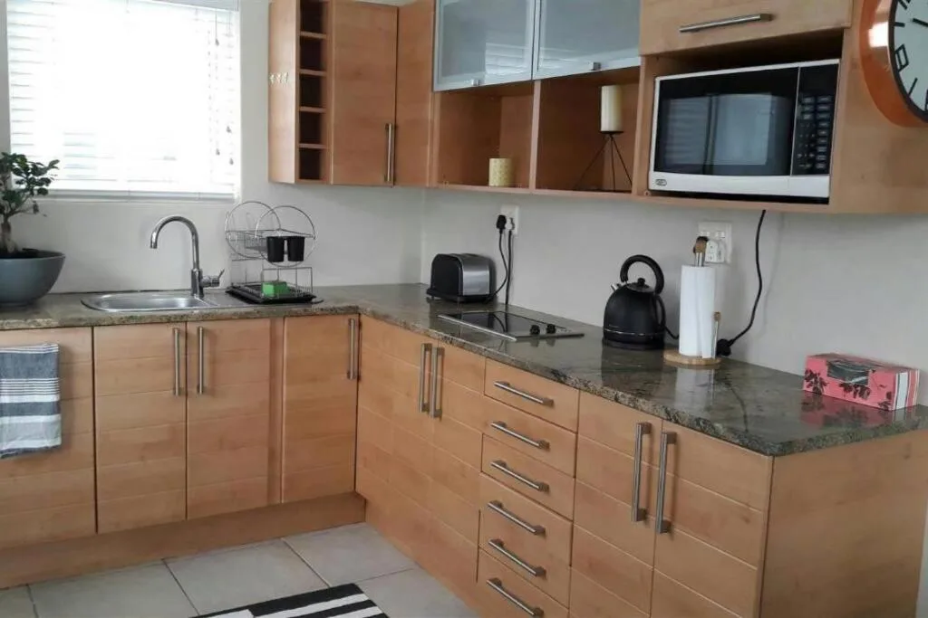 Modern kitchen with wooden cabinetry, granite countertop, and stainless steel appliances