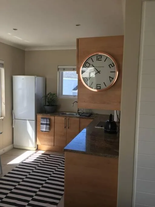 Modern kitchen with white fridge, wooden cabinetry, and wall clock