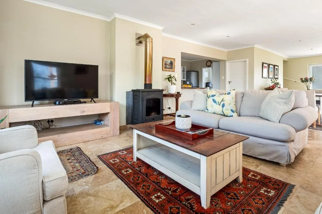 Spacious living room with comfortable sofas, flat-screen TV, and wood stove