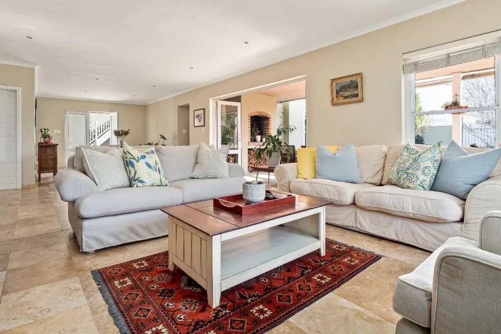 Spacious lounge with cream sofas, decorative pillows, and wooden coffee table