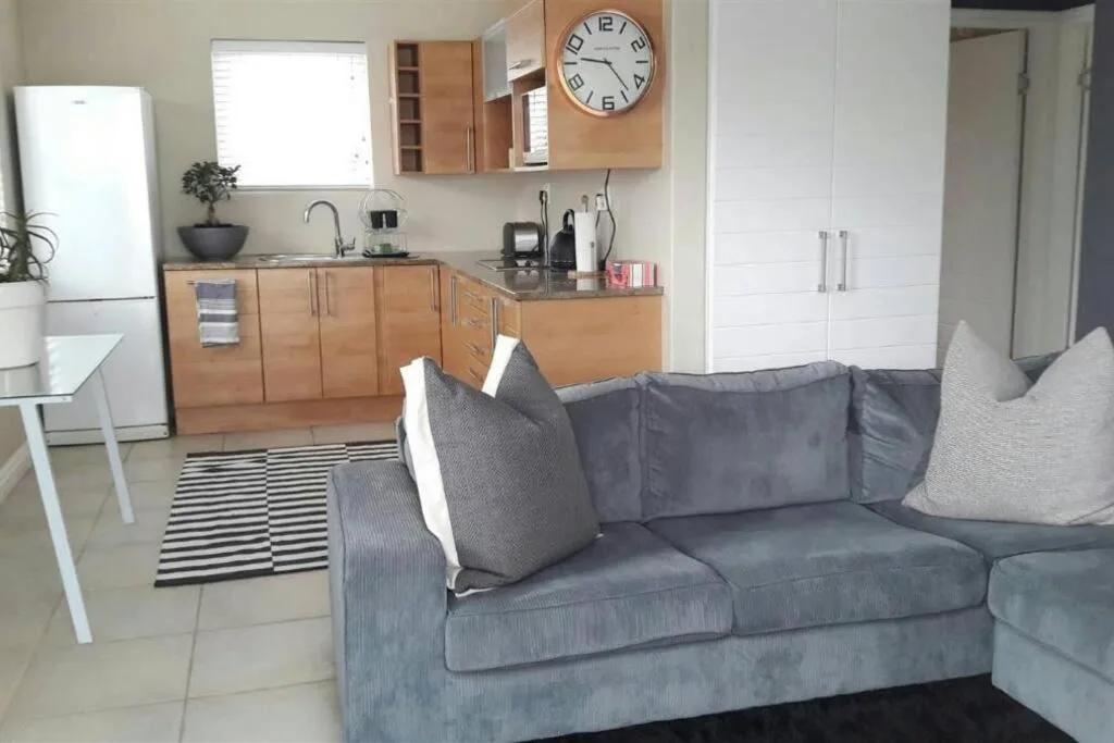Open-plan lounge with grey sofa and kitchen visible in background