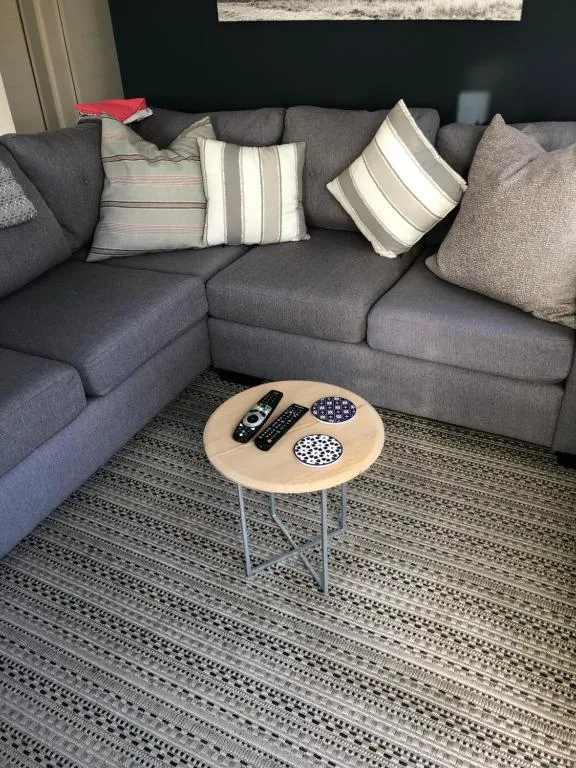 Modern gray corner sofa with striped cushions and small wooden side table