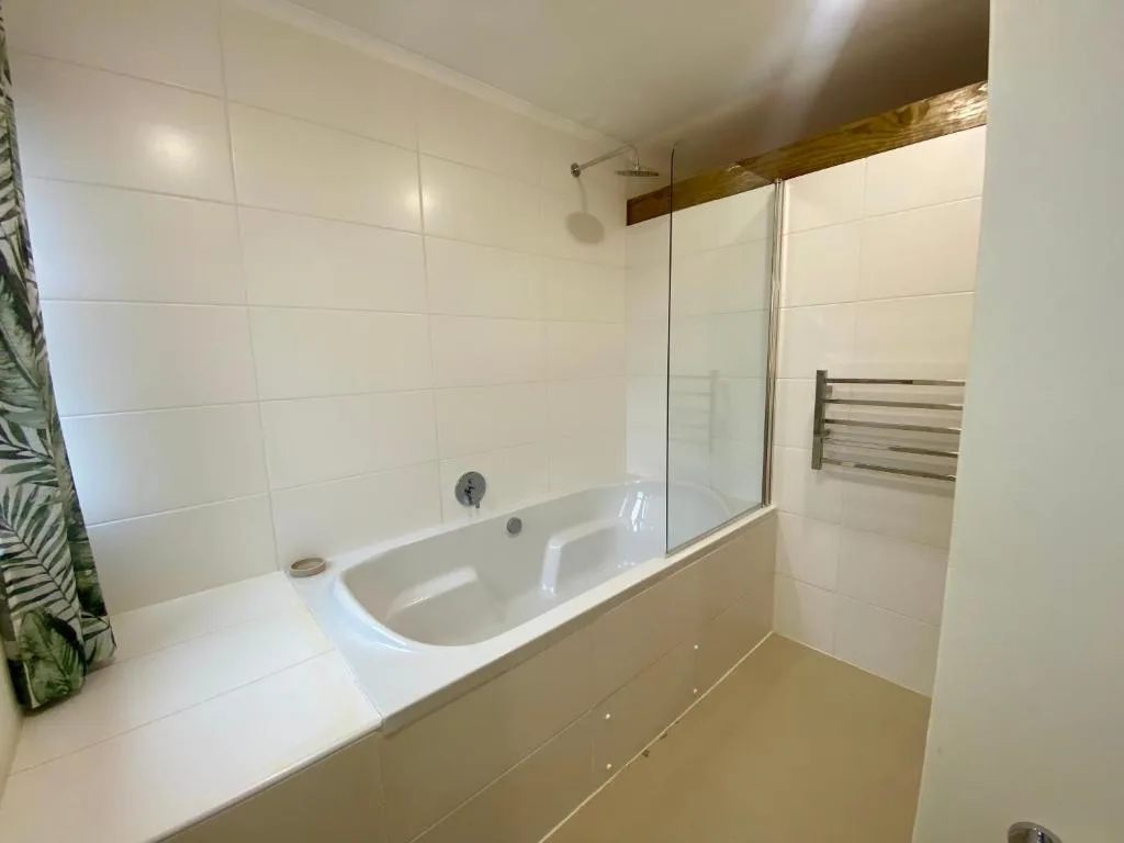 Modern bathroom with white tile walls, curved bathtub and glass shower enclosure