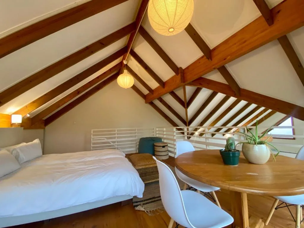 Spacious loft bedroom with exposed wooden beams and pendant lighting fixtures