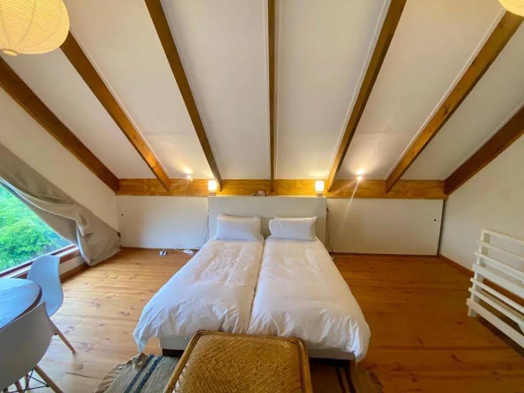 Spacious loft bedroom with two beds and wooden beam ceiling details