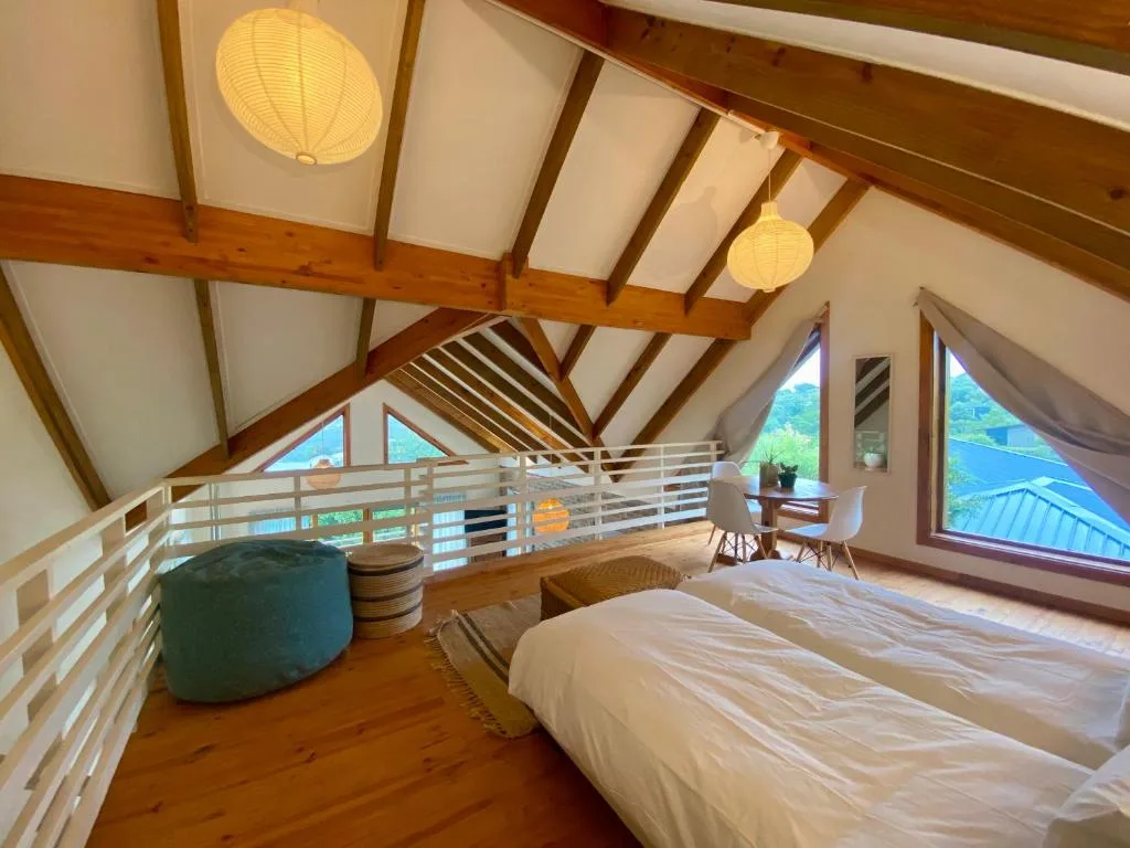 Spacious loft bedroom with vaulted wooden beams and panoramic windows