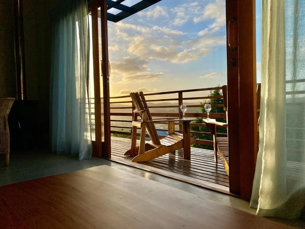 Wooden deck with chairs overlooking scenic landscape at golden sunset hour