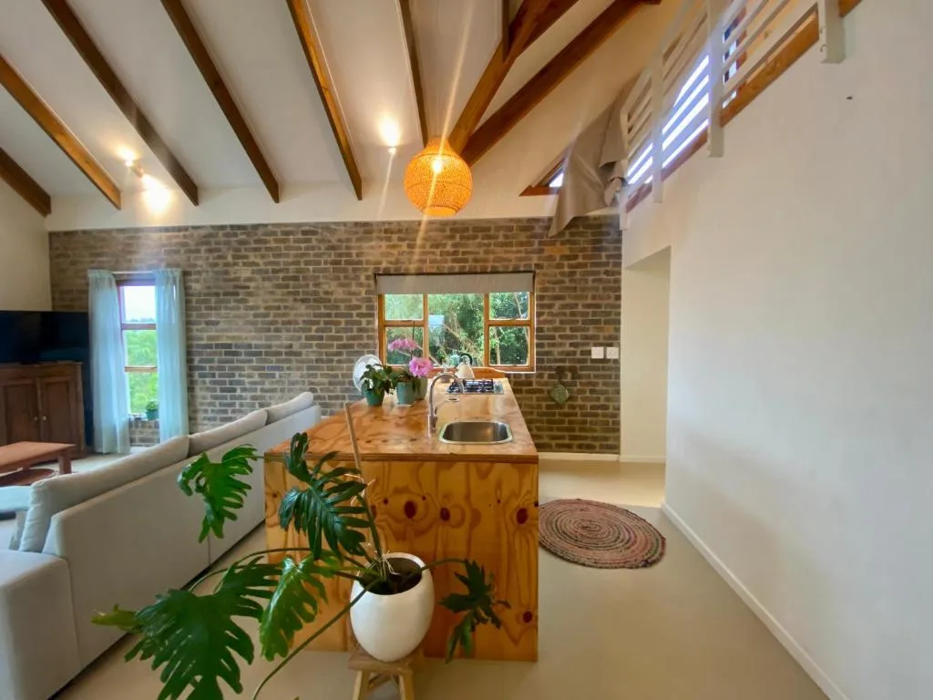 Open-plan kitchen with wooden island, brick feature wall, and exposed beams