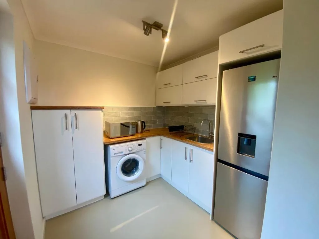 Modern kitchen with white cabinetry, stainless steel refrigerator, and washing machine