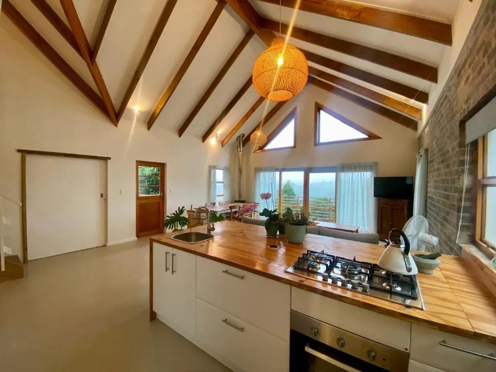 Modern open-plan kitchen with wooden countertop, gas cooktop, and vaulted ceiling
