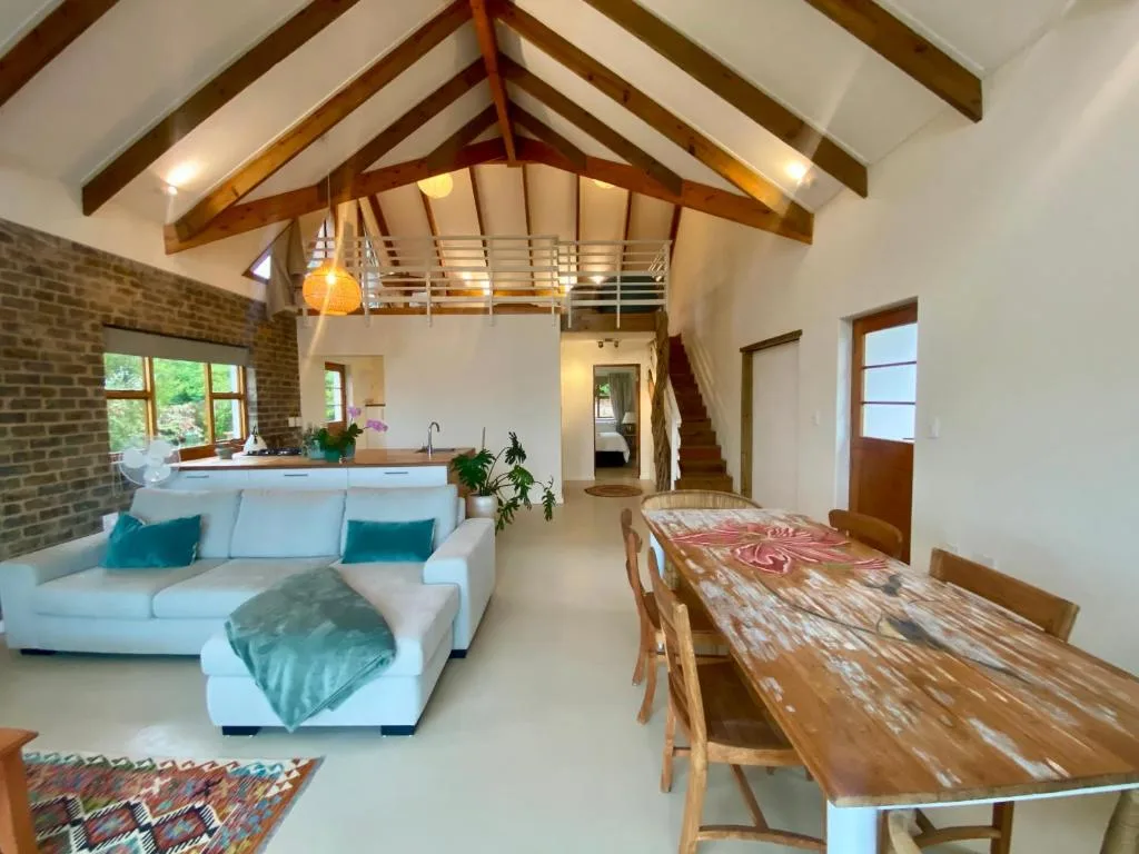 Open-plan lounge with white sofa, exposed wooden beams, and dining area beyond