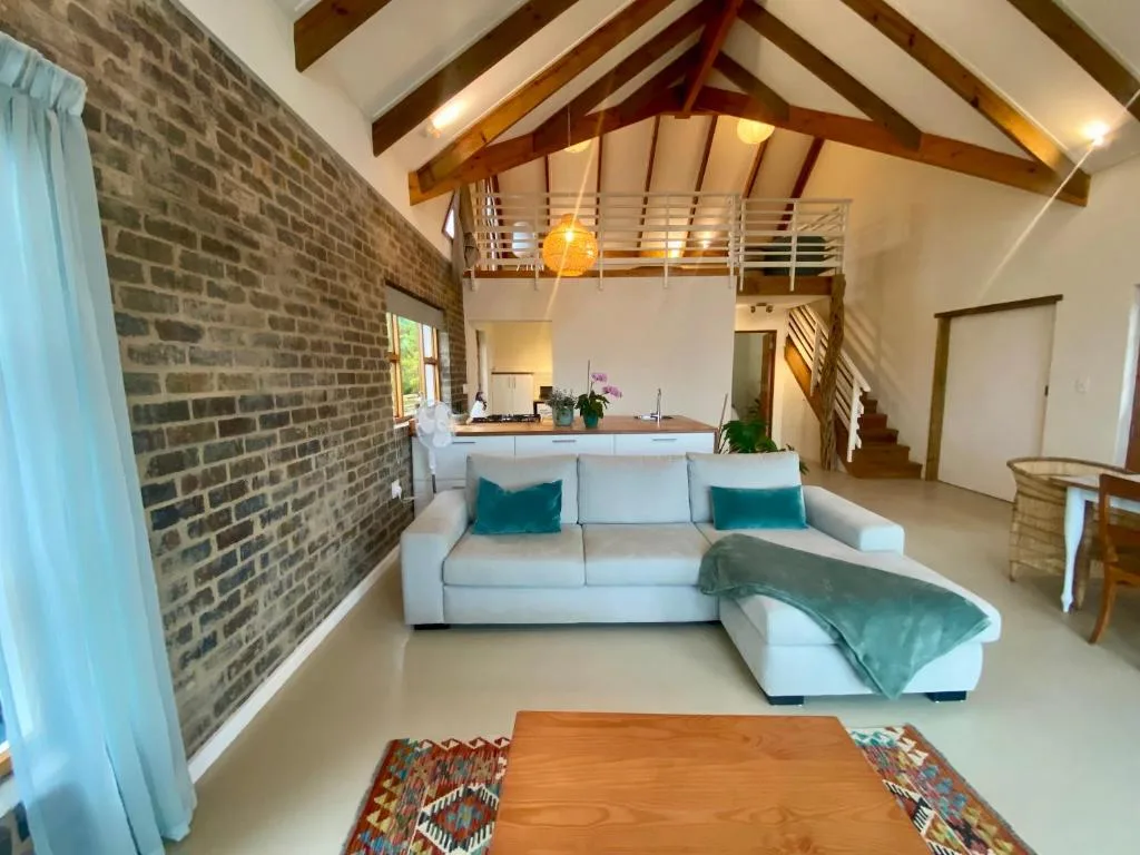Modern open-plan lounge with white sofa, exposed brick wall, wooden beams