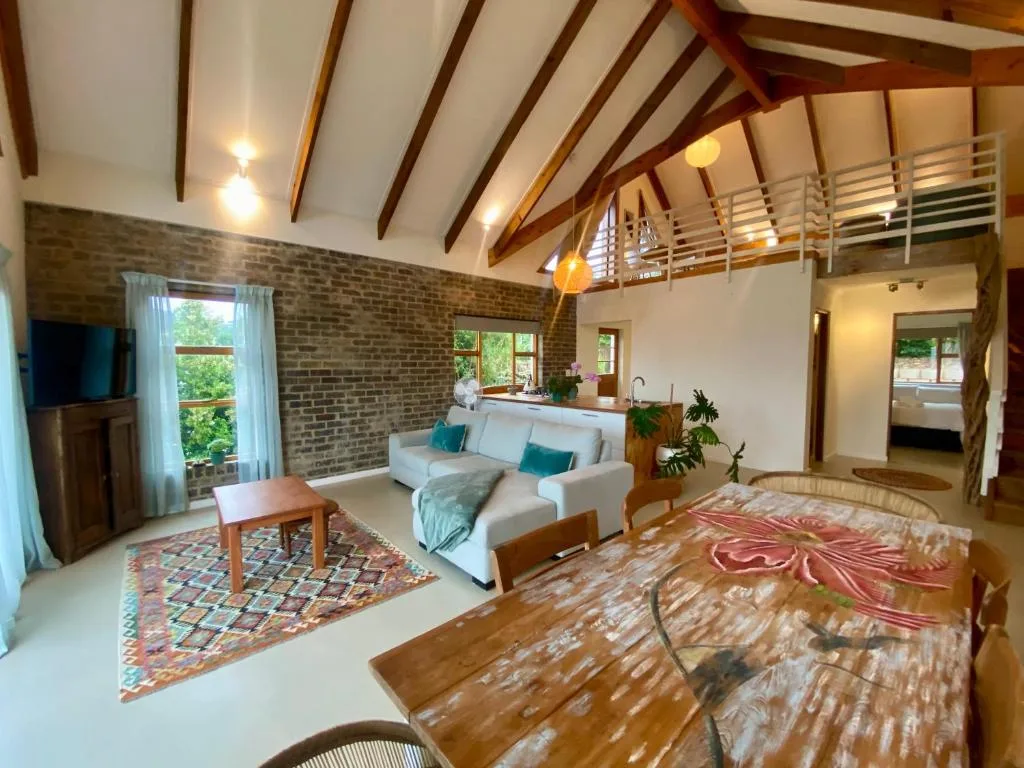 Spacious open-plan lounge with exposed beams, cream sofa, and brick accent wall