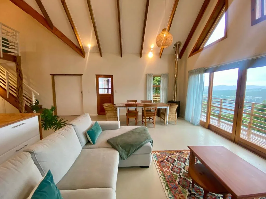 Spacious lounge with cream sofa, exposed beams, and scenic mountain views through glass doors