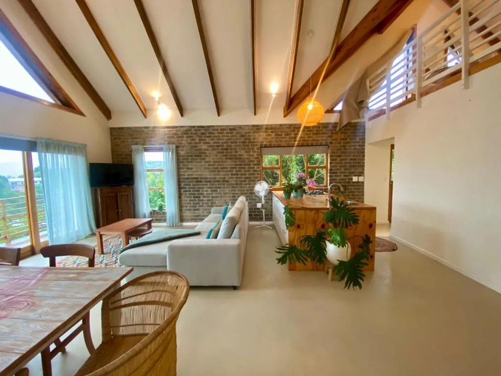 Open-plan lounge with cream sofa, exposed wooden beams, brick feature wall