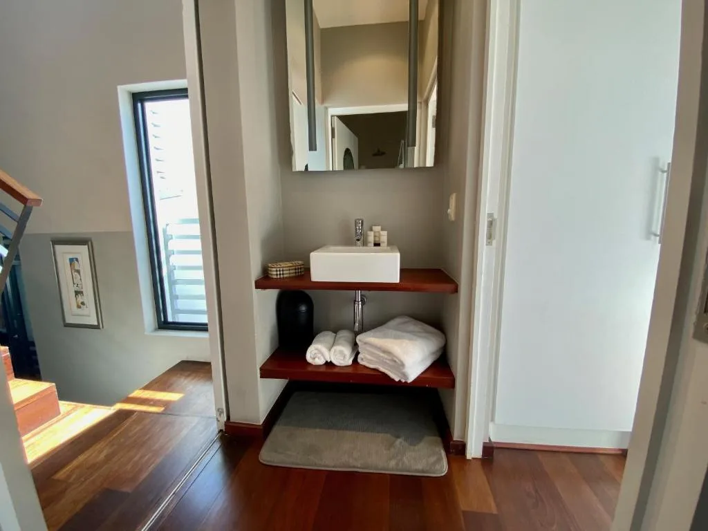 Modern bathroom vanity with white sink and mirror above wooden shelves