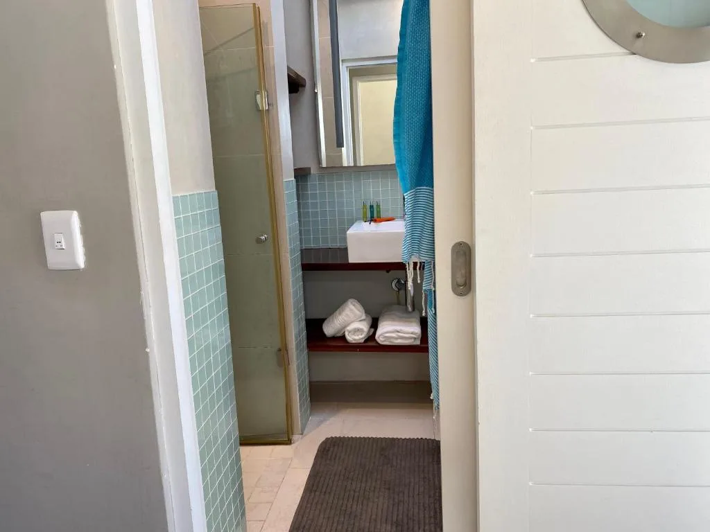 Modern bathroom with shower, sink, and neatly folded towels on shelf