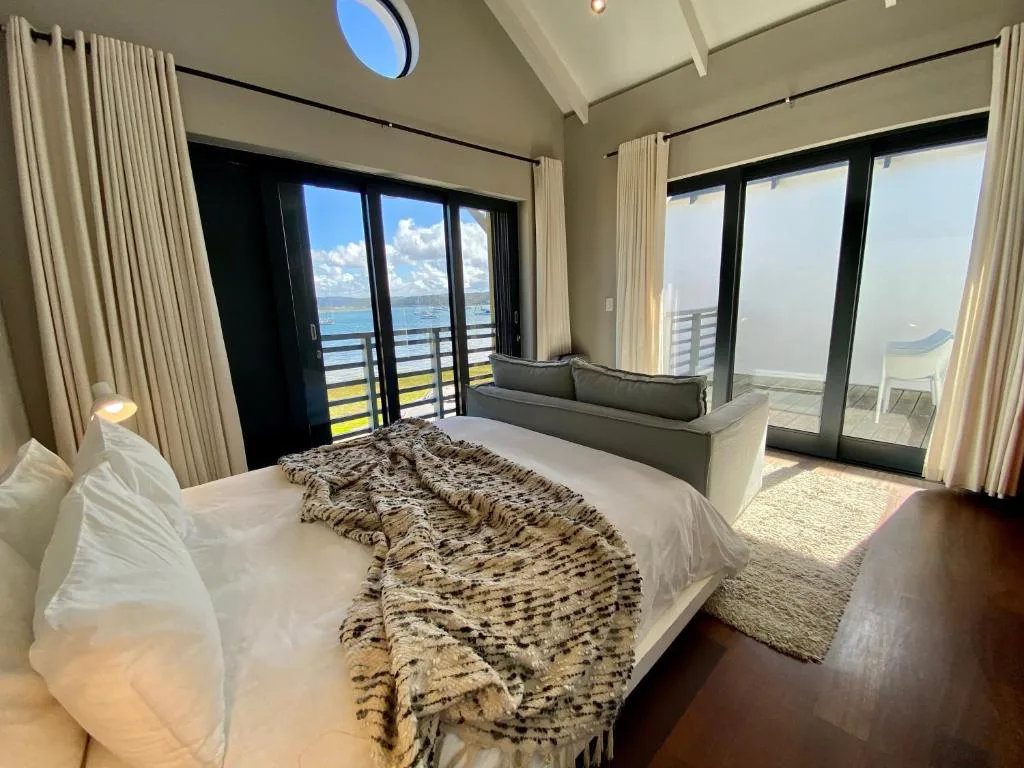 Bright bedroom with ocean views, modern furnishings, and direct deck access