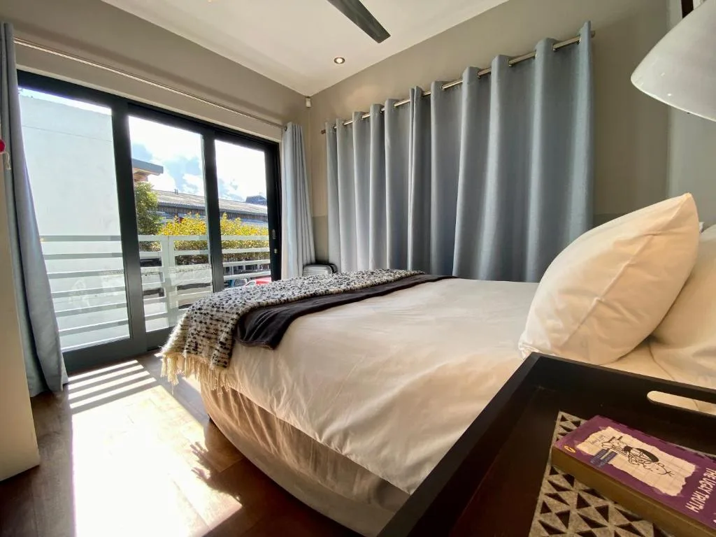 Modern bedroom with white bedding, floor-to-ceiling windows overlooking lagoon views