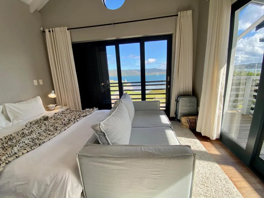 Modern bedroom with ocean and mountain views through glass doors