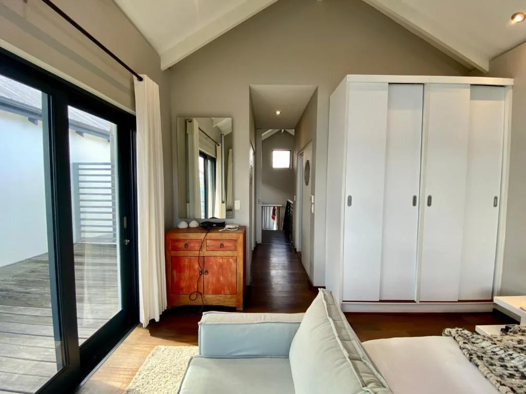 Modern bedroom with bed, sliding wardrobe, wooden dresser, and deck access