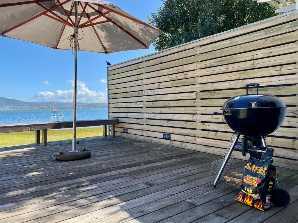Waterfront deck with umbrella, braai grill, and lagoon views beyond