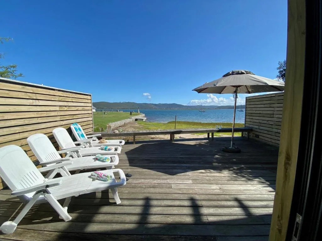 Wooden deck with loungers and umbrella overlooking lagoon and mountains