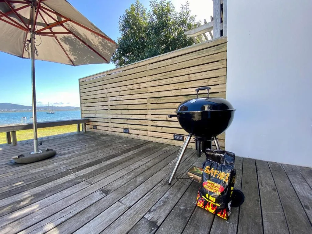 Waterfront deck with braai grill, umbrella, and lagoon views